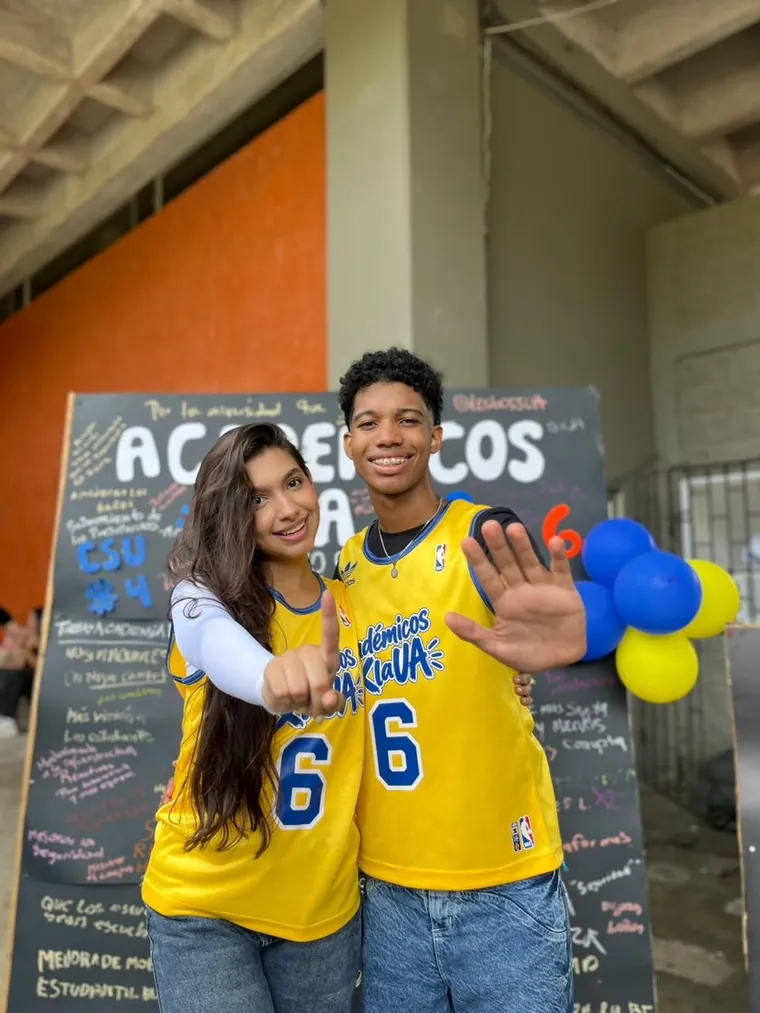 Stephany y Mateo con sus camisetas amarillas número 6, señalando a la cámara